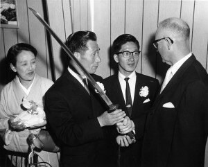 Retired aviator Nobuo Fujita presents his family’s 400-year-old sword to Brookings Mayor Fell Campbell as his wife, Ayako, and son, Yasuyoshi, look on. CREDIT: Bombs Over Brookings/William McCash.